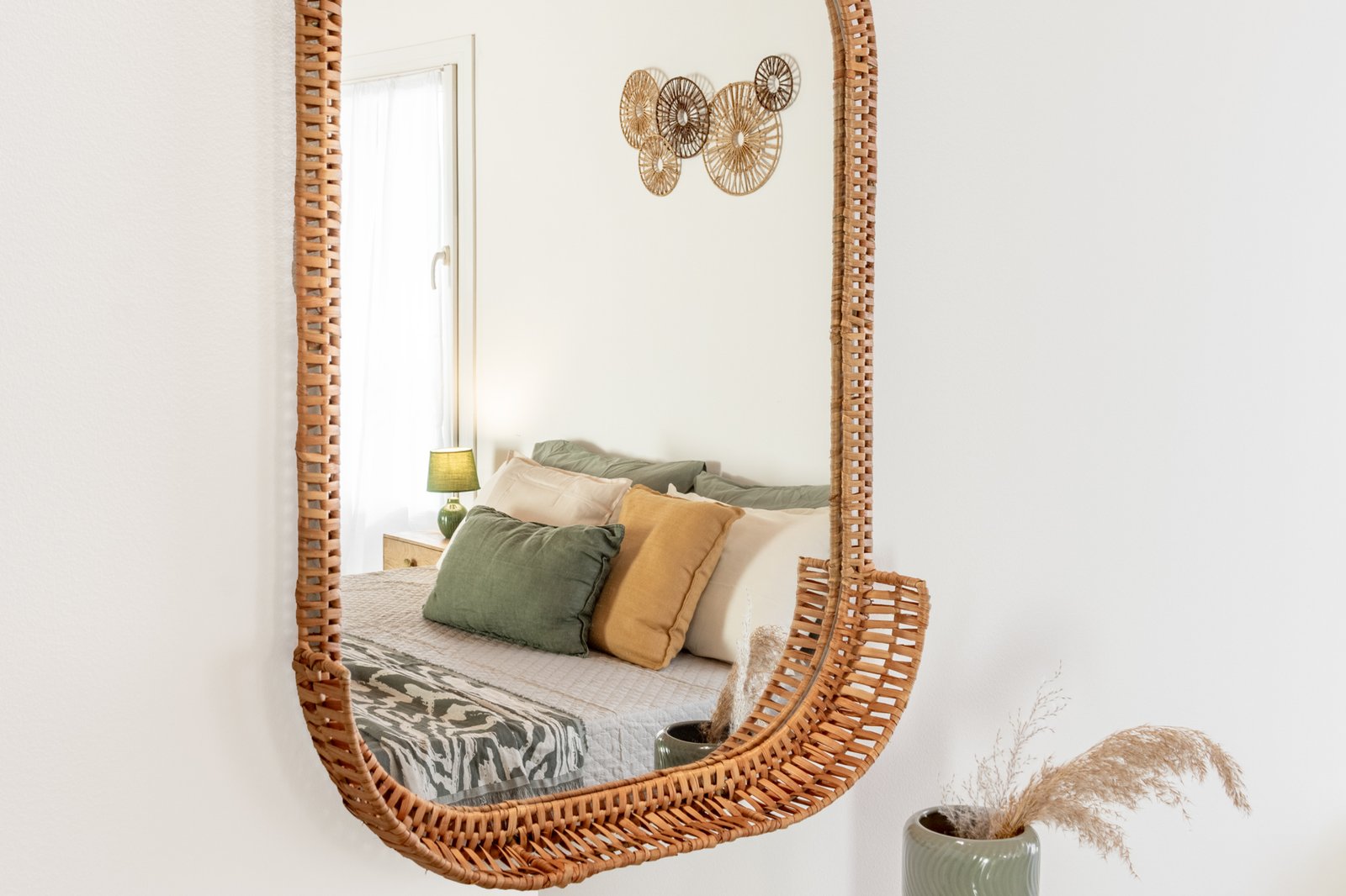 11_home-staging-camera-letto-dettaglio-cuscini-verdi-senape-specchio-vimini.jpg Dettaglio della camera da letto con cuscini nei toni del verde e del senape, riflessi nello specchio intrecciato in vimini, accanto a un vaso decorativo con ciuffi naturali, in un insieme elegante e dal gusto caldo e contemporaneo.