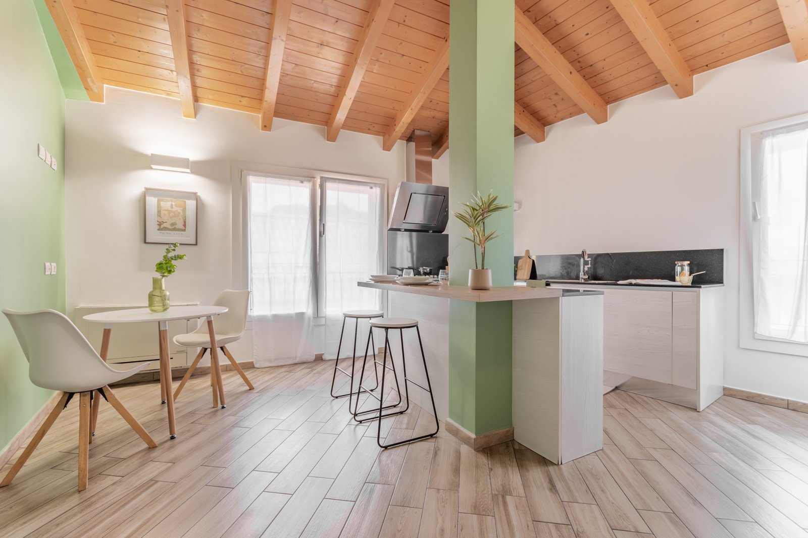 13_home-staging-cucina-moderna-mansardata-travi-legno-salvia-isola-tavolo-rotondo.jpg Cucina mansardata con travi in legno a vista,parete e colonna centrale color salvia, caratterizzata da un blocco cucina moderno, isola centrale con sgabelli minimal e tavolo rotondo con sedute bianche e legno. L’atmosfera è calda, luminosa ed elegantemente contemporanea.