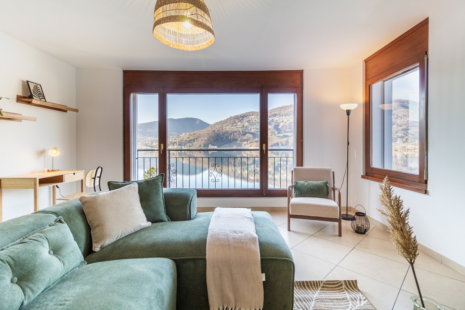 2_relooking-appartamento-soggiorno-moderno-elegante-vista-lago-divano-verde-toni-neutri.jpg Living room con divano verde e poltrona beige, vista panoramica sul lago e atmosfera calda e rilassata.