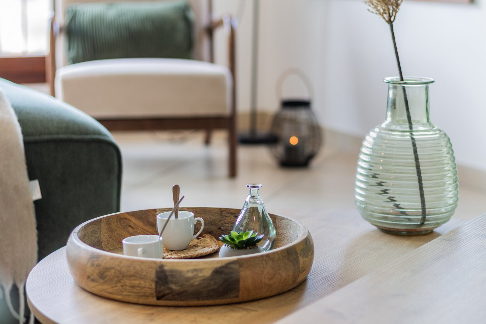 3_dettaglio-tavolino-soggiorno-decorazioni-naturali-vetro-legno.jpg Dettaglio del tavolino con vassoio in legno e vaso in vetro, decorazioni naturali e minimaliste.