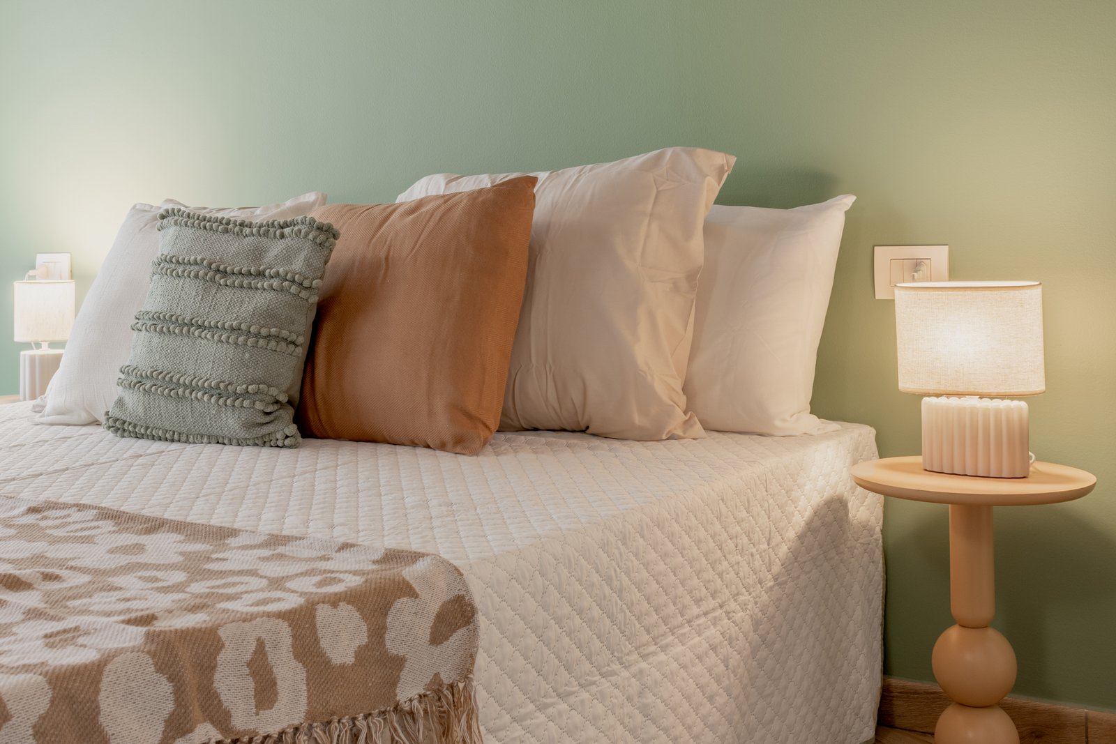 4_home-staging-camera-letto-dettaglio-cuscini-beige-senape-salvia-comodino-design.jpg Dettaglio della camera da letto mansardata con cuscini nei toni del beige, senape e salvia, accostati a un comodino dal design moderno e scultoreo e a una abat-jour con luce calda che crea un’atmosfera intima e raffinata.