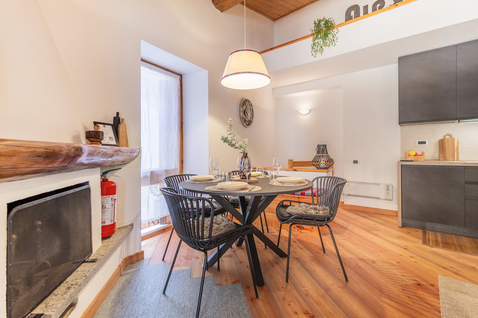 4_relooking-appartamento-montagna-zona-pranzo-moderno-design-legno-elegante.jpg Zona pranzo moderna con tavolo rotondo nero e lampada sospesa, ambiente luminoso e accogliente con dettagli in legno e stile contemporaneo; appartamento elegante e accogliente.