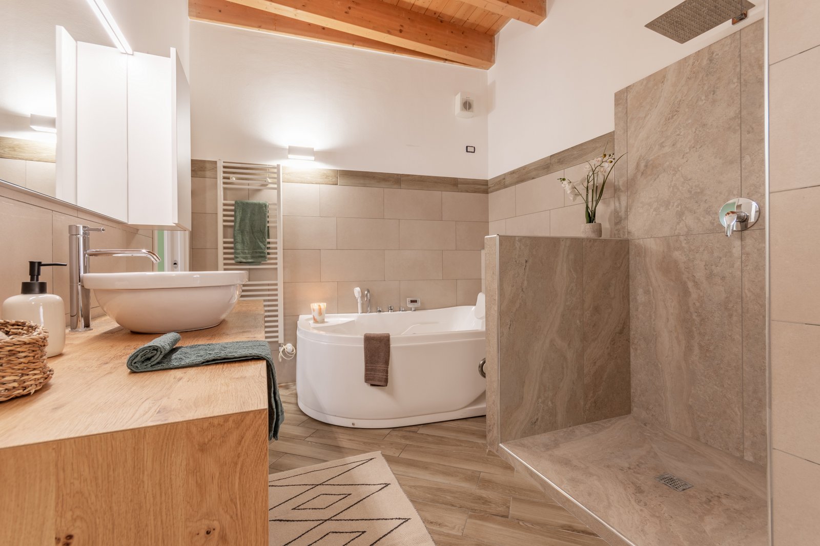 5_home-staging-bagno-vasca-idromassaggio-mobile-legno-miele-marmo-tortora.jpg Bagno elegante con vasca idromassaggio, mobile in legno color miele e lavabo bianco, completato da una doccia a parete rivestita in piastrelle effetto marmo tortora, per un ambiente raffinato e contemporaneo.