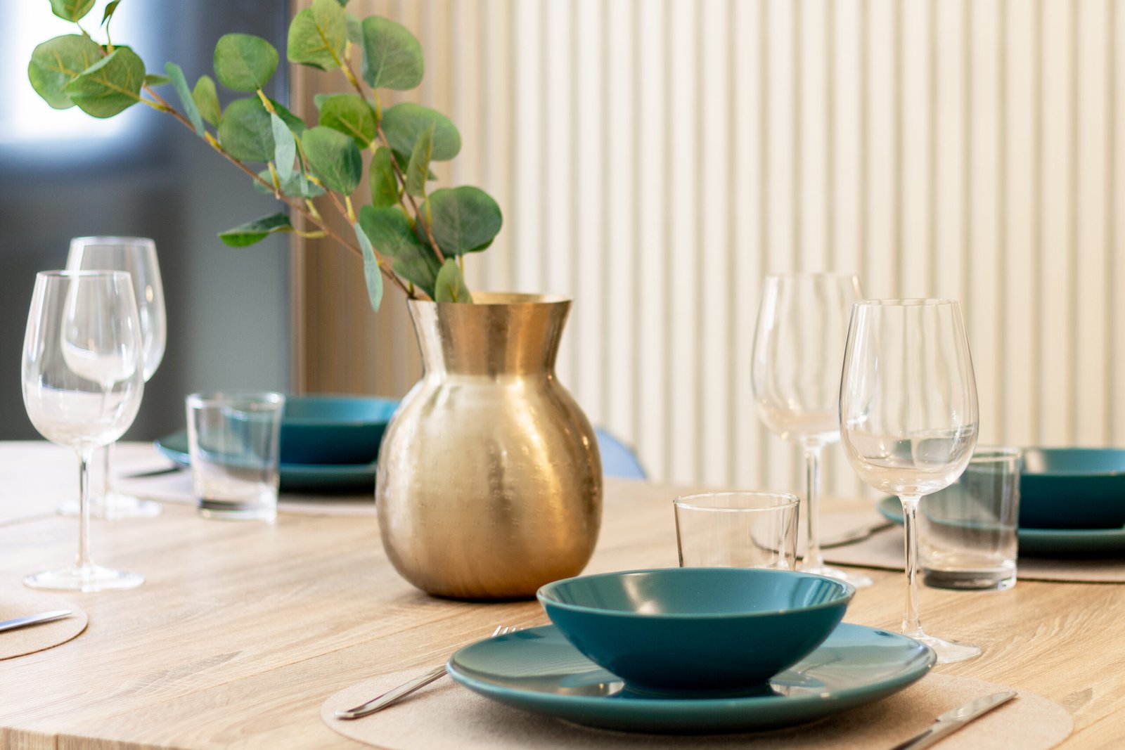 5_relooking-tavola-apparecchiata-elegante-piatti-petrolio.jpg Dettaglio di tavola apparecchiata elegante con piatti color petrolio, calici in vetro, vaso oro opaco ed eucalipto in allestimento home staging dai toni caldi.