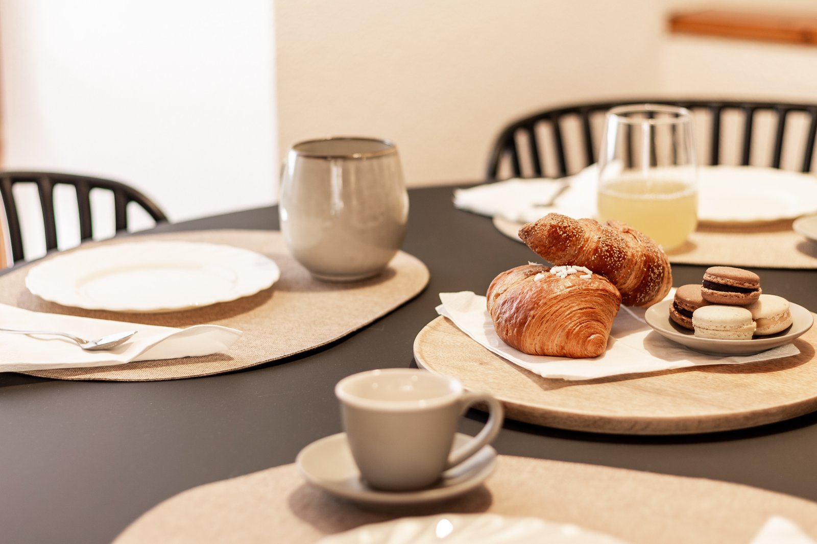 8_dettaglio-tavolo-colazione-accoglienza-cura-eleganza.jpg Dettaglio di tavolo moderno apparecchiato per la colazione con croissant, macarons e bevande, atmosfera raffinata e accogliente.