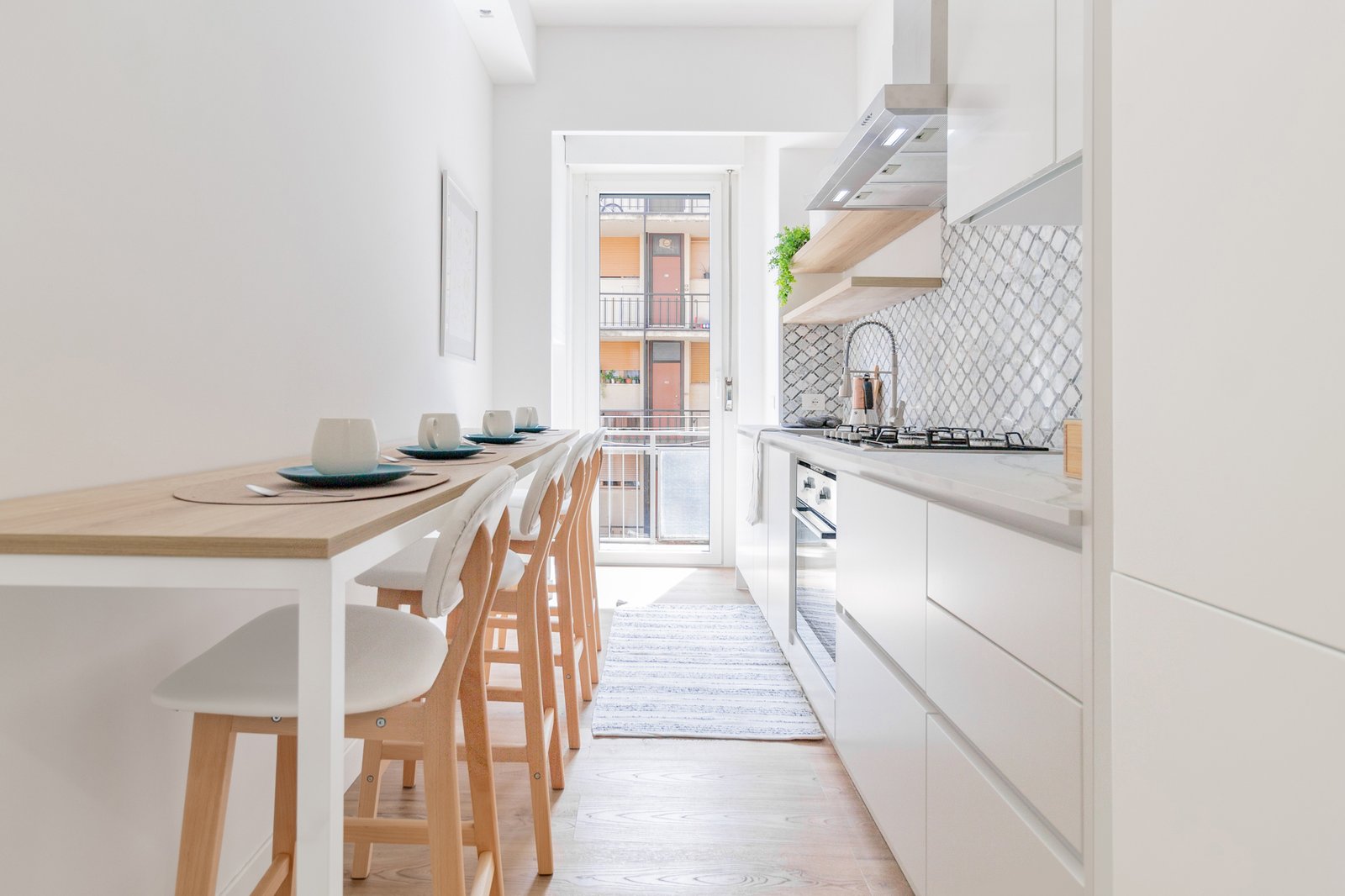 8_relooking-cucina-bianca-moderna-minimal-con-penisola-piastrelle-geometriche.jpg Cucina moderna e luminosa con penisola in legno chiaro,sedie bianche, piastrelle geometriche e mobili bianchi, ambiente minimalista.