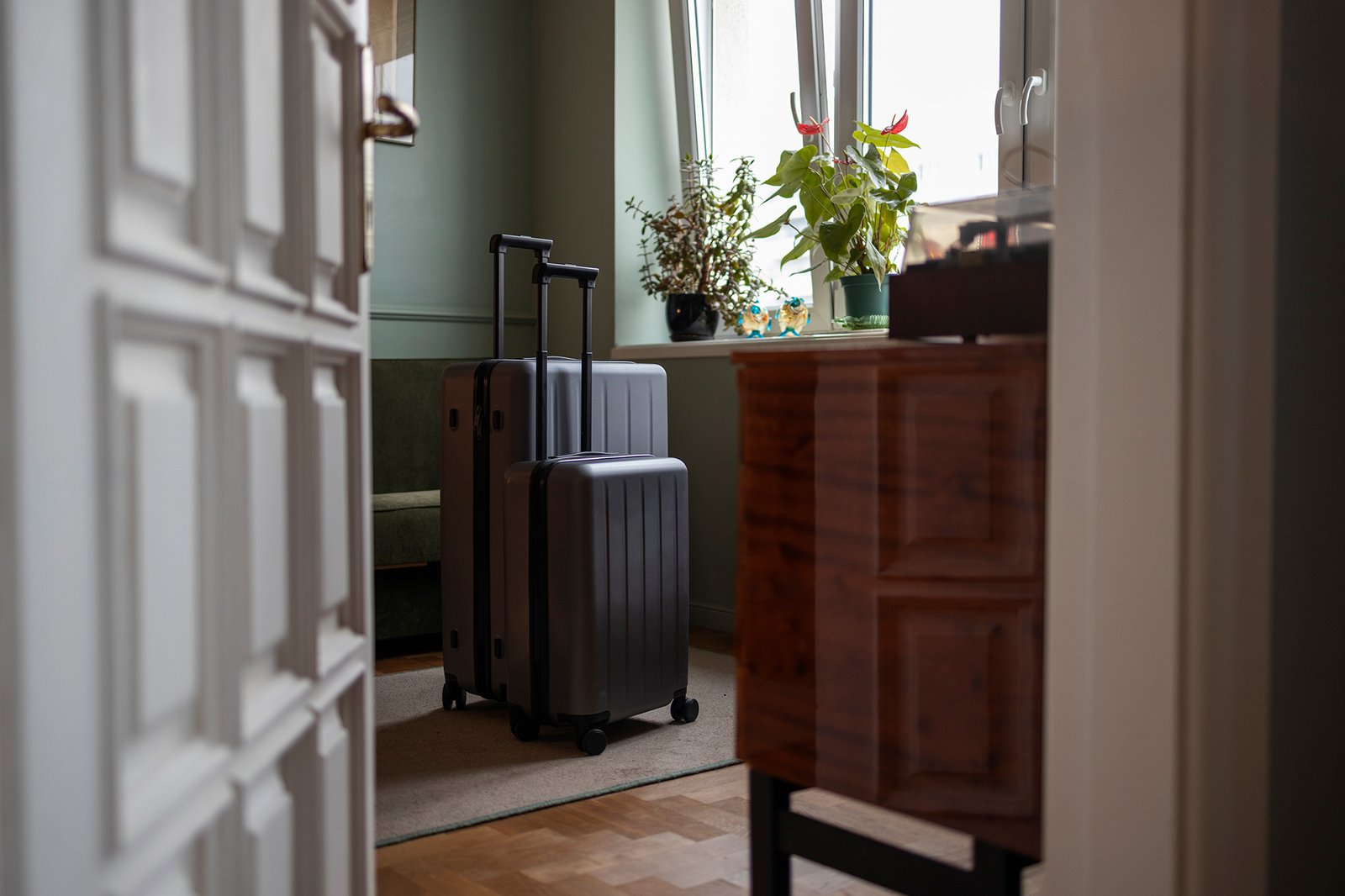 Cucina e zona pranzo moderna e minimalista con pareti bianche e azzurre, pavimento in legno chiaro e arredi dalle linee pulite; tavolo bianco con sedie grigie e gambe in legno, cucina con mobili bianchi e piano in legno, decorazioni con piante verdi e accessori naturali, ambiente luminoso.